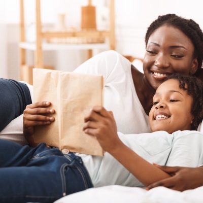 Happy afro family reading book in bedroom